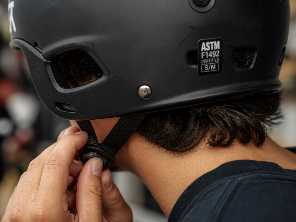 Close-up of hands adjusting chin strap on a downhill skateboarding helmet