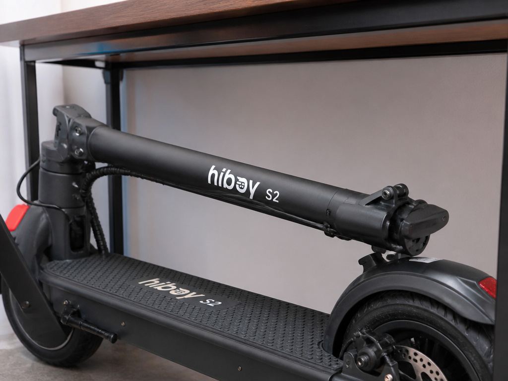 Folded Hiboy S2 electric scooter stashed under a desk, showing portability.