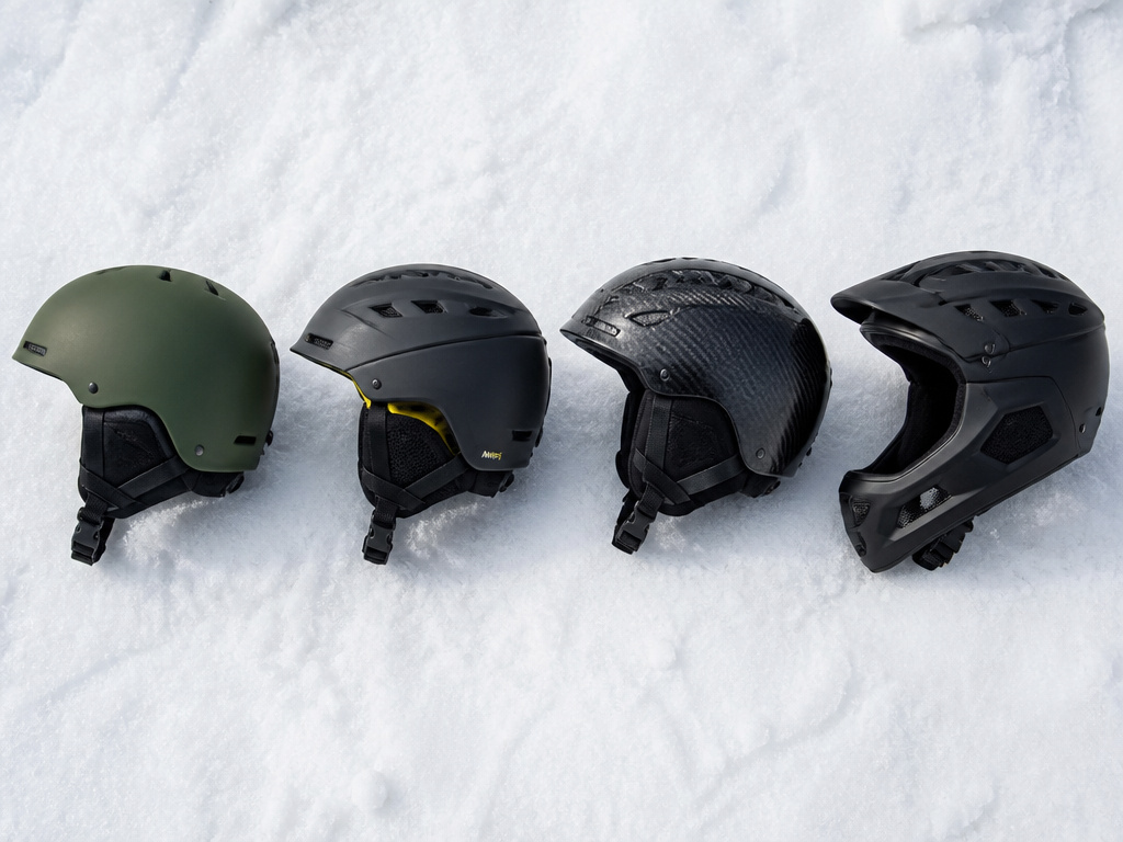 Four tiers of snowboard helmets from budget to premium laid on snow.