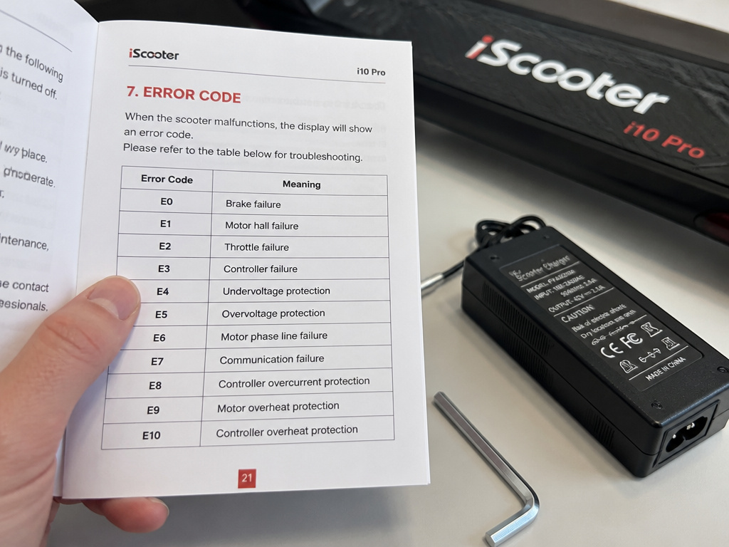 iScooter i10 Pro manual with error codes, charger, and tools on table