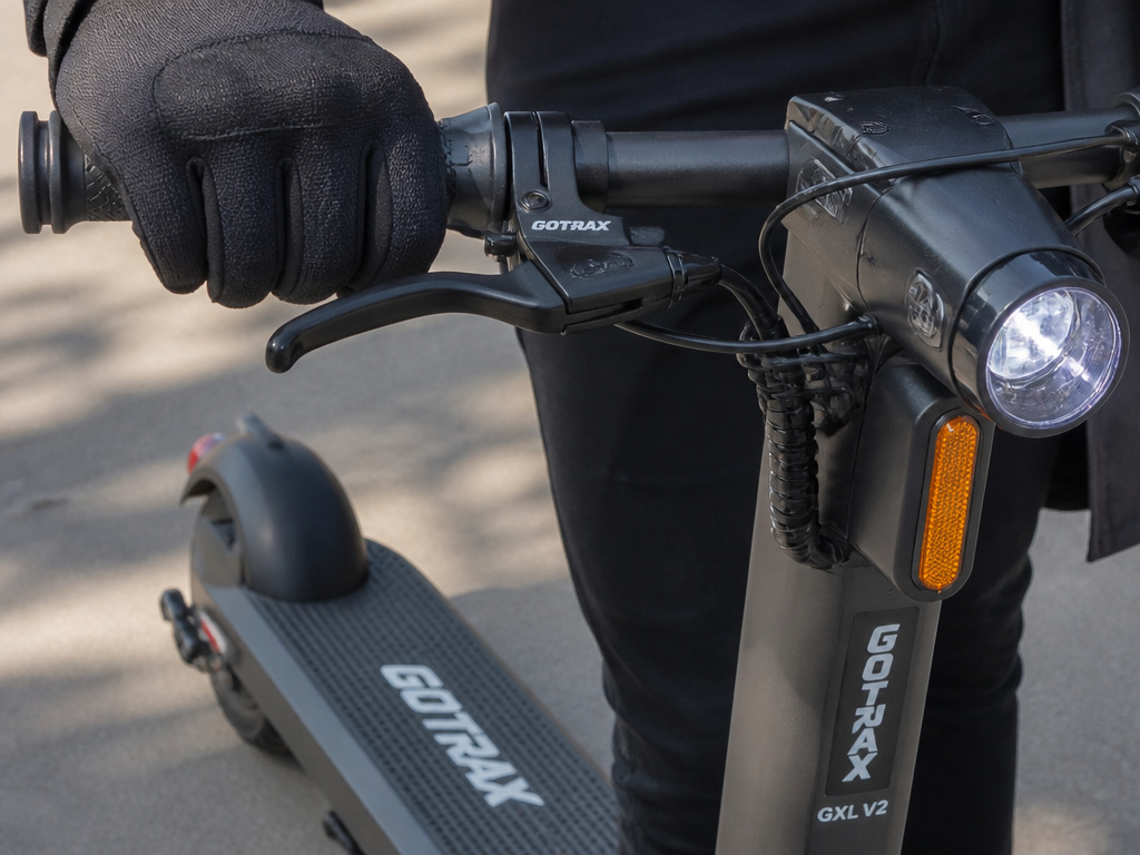 Close-up of GoTrax GXL V2 brake lever, headlight, and safety features in use.