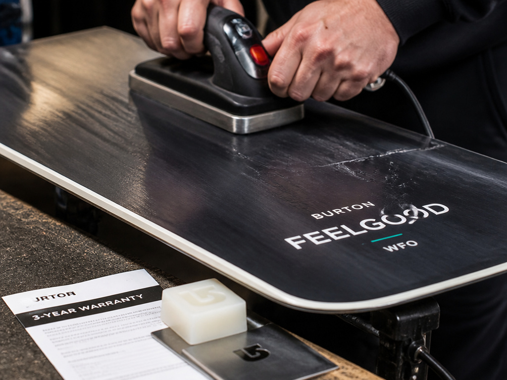 Close-up of waxing a Burton Feelgood snowboard's durable sintered base.