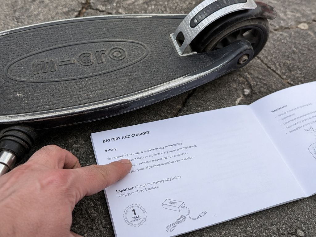 Close-up of Micro scooter footboard wear and battery warranty details in manual.