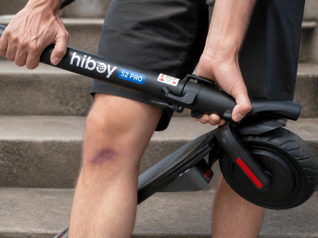 Close-up of folded Hiboy scooter being carried, showing potential shin hazard.
