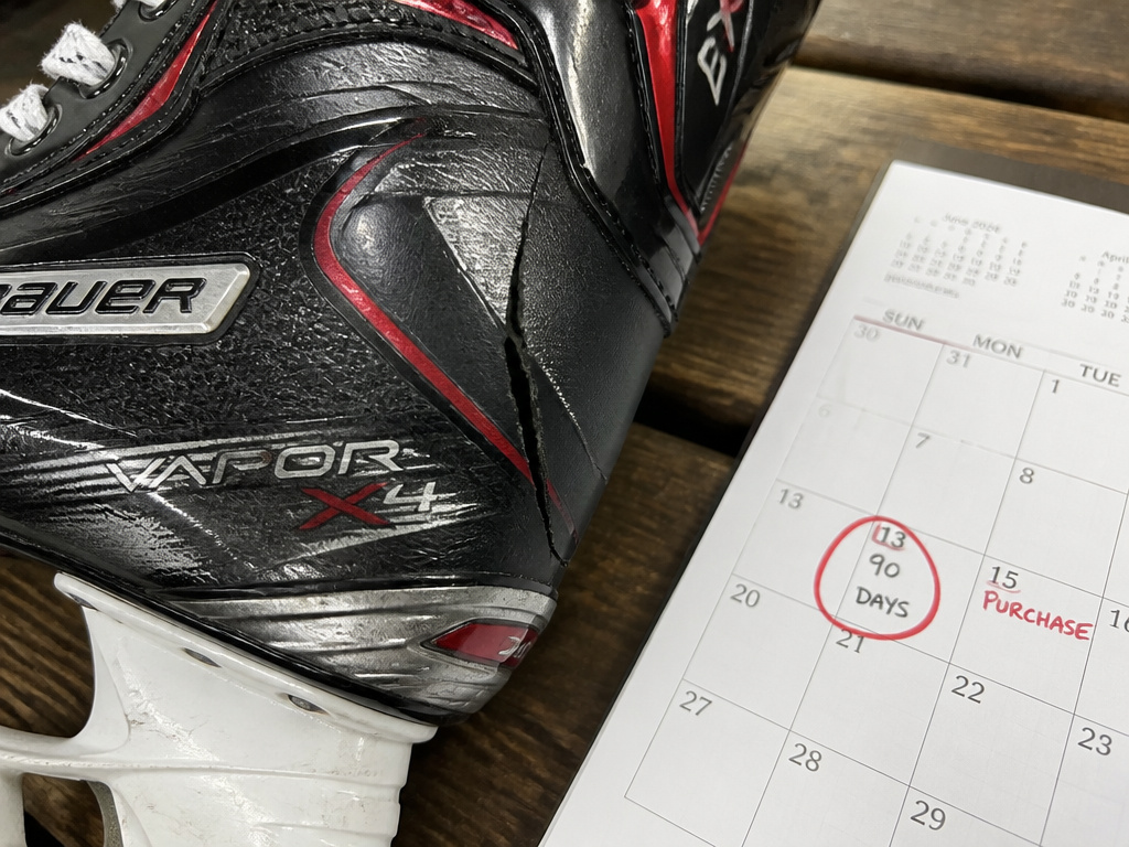 Close-up of cracked tendon guard on Bauer Vapor X4 skate next to 90-day calendar