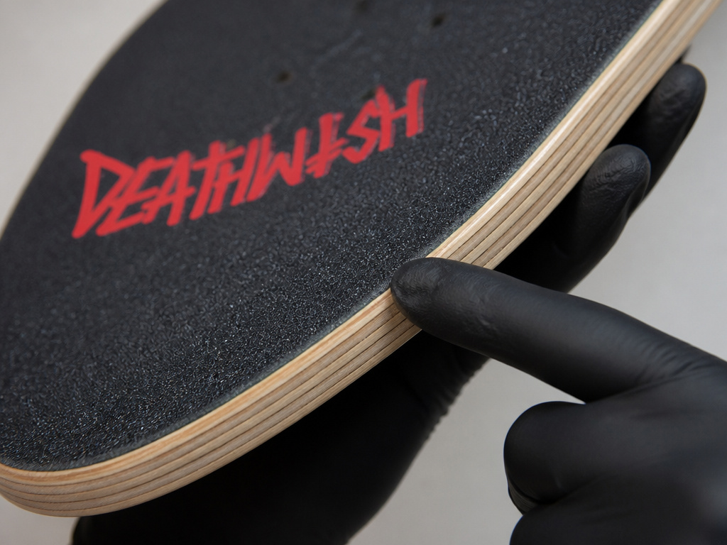 Close-up of a Deathwish skateboard deck showing its 7-ply maple construction layers.