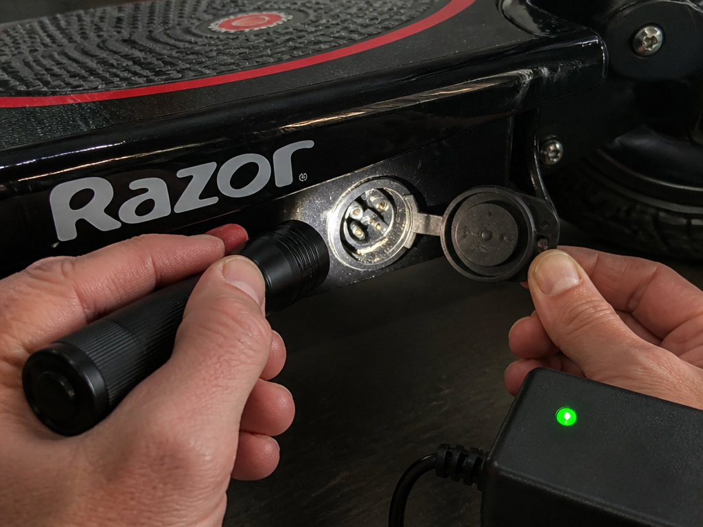 Close-up inspection of a Razor scooter's charging port for debris or damage.