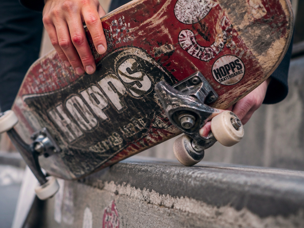 Close-up of a Hopps skateboard deck grinding on a city curb during a tailslide.