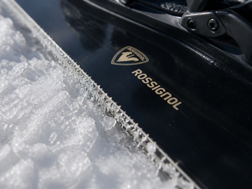 Close-up detail of a Rossignol snowboard's serrated edge and sintered base on hard snow.