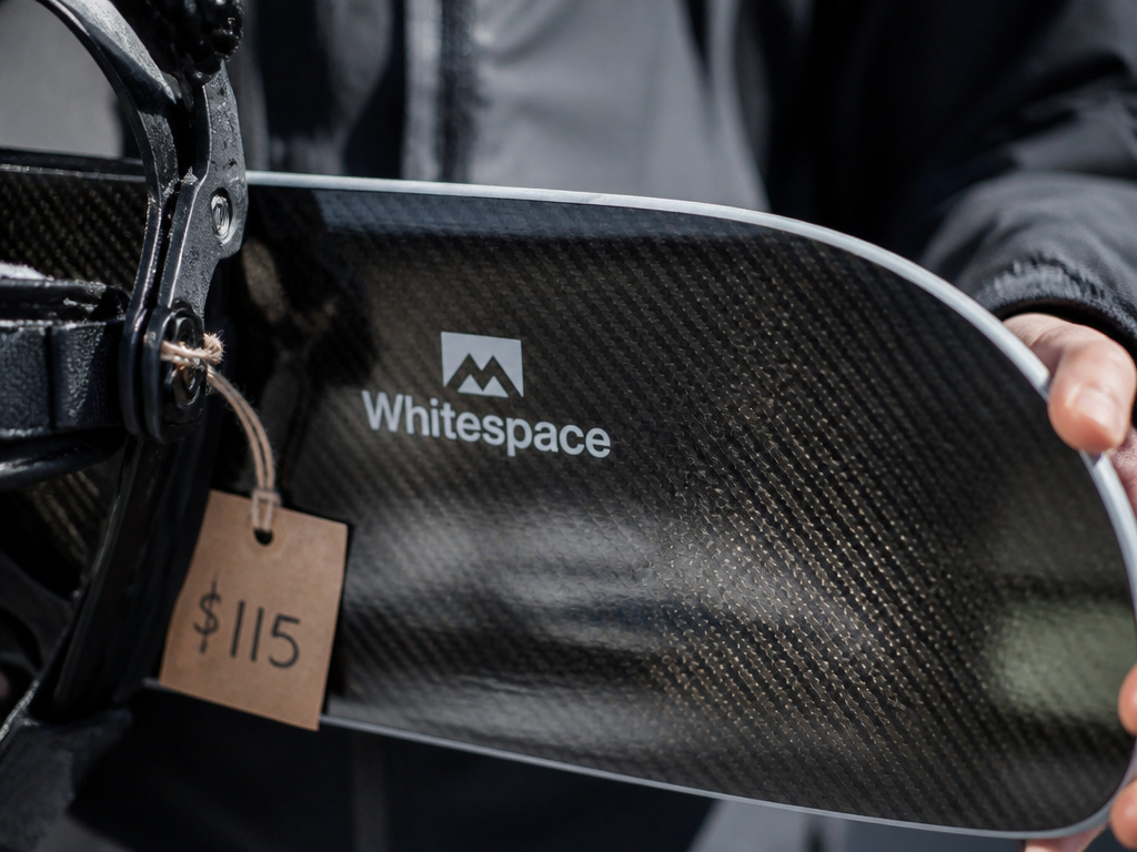 Close-up of discounted Whitespace snowboard with price tag and carbon fiber detail