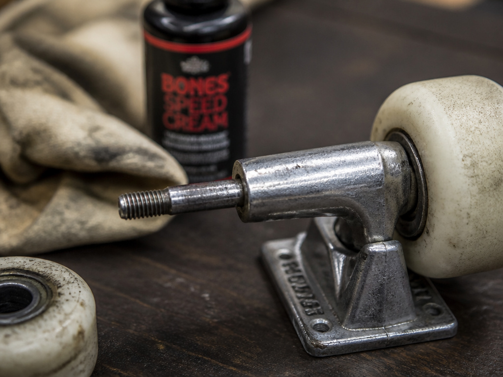 Close-up of a steel skateboard axle showing wheel mounting and maintenance tools.