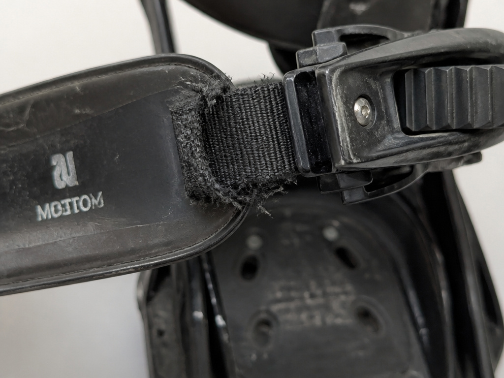 Close-up of a frayed snowboard binding ankle strap showing common wear and tear.