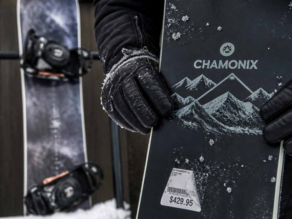 Close-up of budget Chamonix snowboard compared to used premium board in snow.