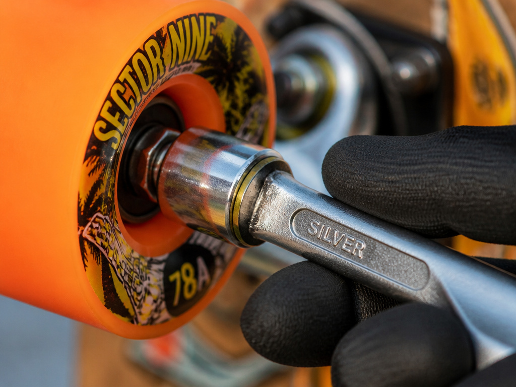 Close-up of tightening a longboard wheel nut with a skate tool.