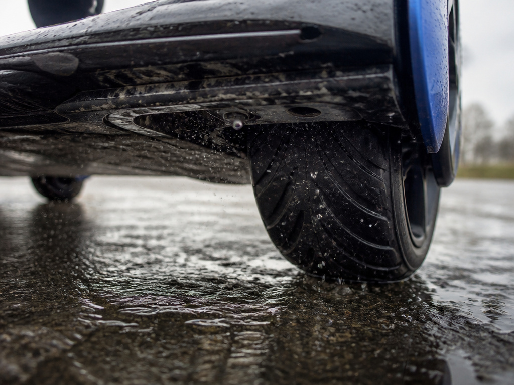 Hoverboard tire spraying water mist onto its electronics on wet pavement.