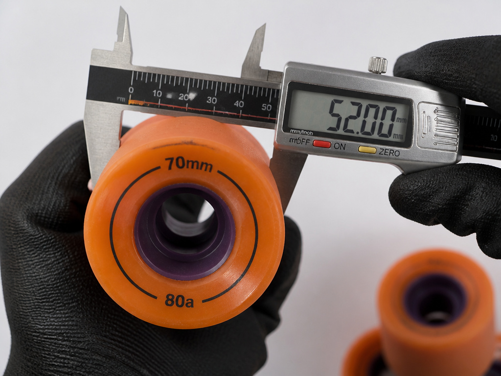 Measuring longboard wheel diameter and width with a caliper tool.