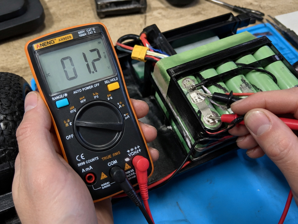 Using a multimeter to test a dead hoverboard lithium-ion battery pack voltage.